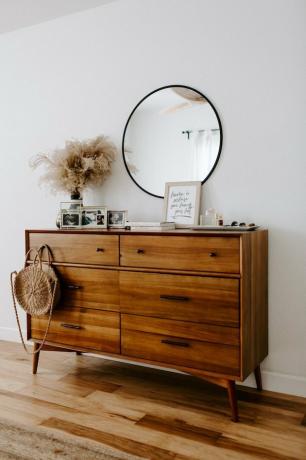 slaapkamer met houten dressoir en ronde spiegel