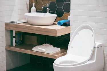 Moderne romslig bad med lyse fliser med toalett og vask. Sett fra siden