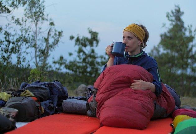 Mulher bebendo contra o céu durante o pôr do sol