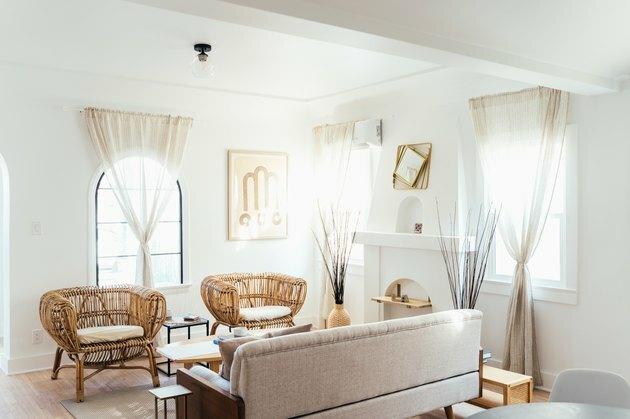 baltos spalvos idėja gyvenamajame kambaryje su rotango baldų kėdėmis, skaistalų sofa ir medžio akcentais