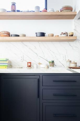 vedere a bucătăriei moderne cu dulapuri de bucătărie negre, rafturi de perete deschise pe spate din piatră albă