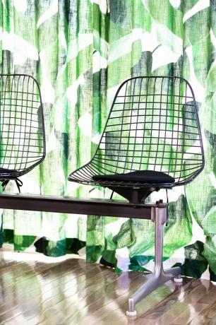 Cadeiras de arame Eames contra cortinas estampadas de folhas