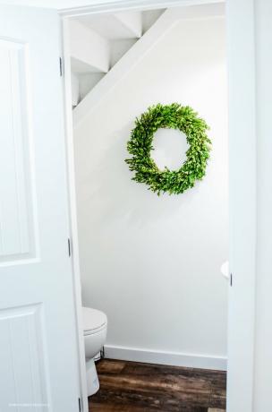 Badkamer onder trap met witte muren en groene buxus krans