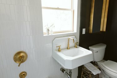 pesuallas kultaisella hanalla ja mustalla seinällä kylpyhuoneessa