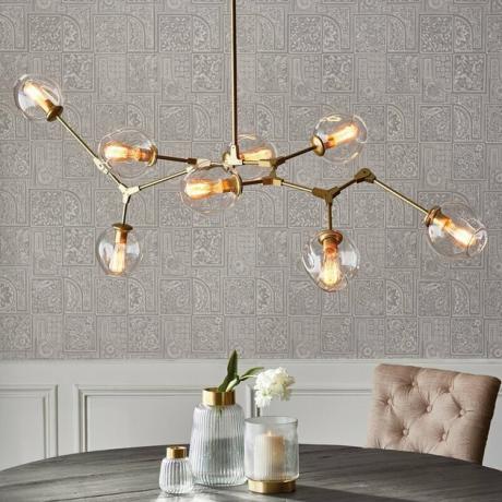Iluminação contemporânea da sala de jantar em latão e vidro com lustre de ramos sobre a mesa