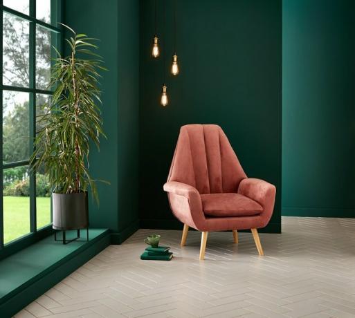 sala com paredes verdes profundas e cadeira rosa