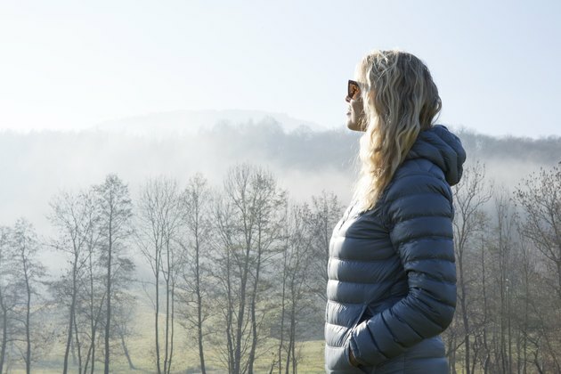Vrouw loopt door heuvelachtige weide in mist