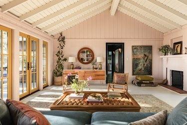 Soggiorno con soffitto a telaio con mobili color terra, decorazioni eclettiche e portefinestre gialle.
