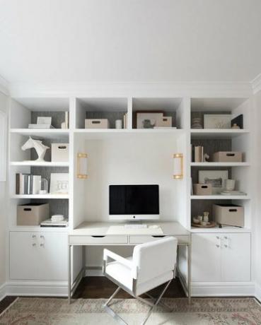 moderan bijeli kućni ured s ugrađenim policama i mesinganim zidnim pločama