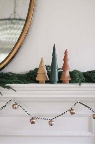 DIY sleigh bell krans hang under mantel dekorert med tre juletrær