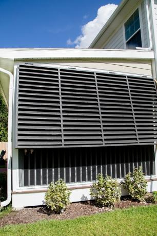 Estilo de obturador exterior preto Bahama na casa tradicional, ao lado de paisagismo