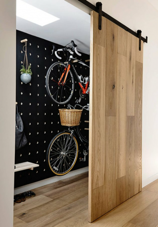 Portas de celeiro contemporâneas de madeira clara, arrecadação para bicicletas, claraboia.