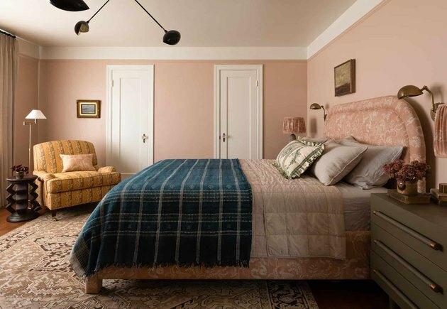 ideia de quarto rosa com cadeira ocre e cama rosa com manta azul marinho