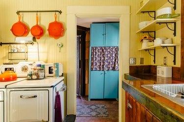 Krāsaina, vintage virtuve ar dzeltenām sienām, retro plīti un oranži ziliem akcentiem
