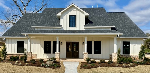 فكرة المنزل الخارجي التقليدية للمنزل الأبيض مع إضاءة مميزة على الشرفة الأمامية
