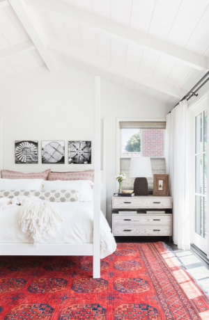 غرفة نوم ذات سقف مقوس أبيض وفراش أبيض مع سجادة باللون القرمزي.