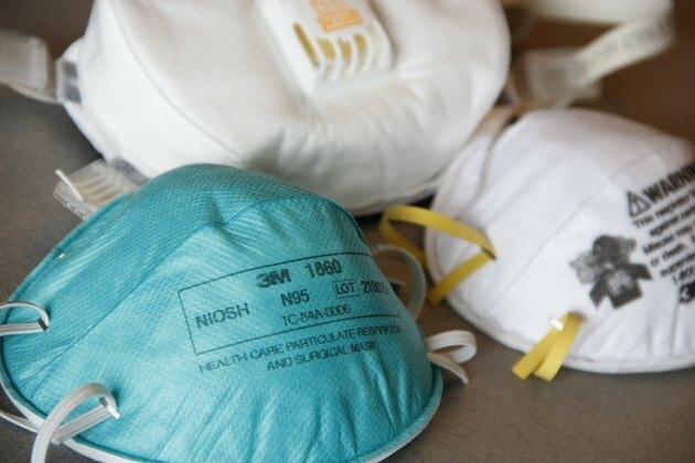 máscara facial n95 azul ao lado de duas máscaras faciais brancas