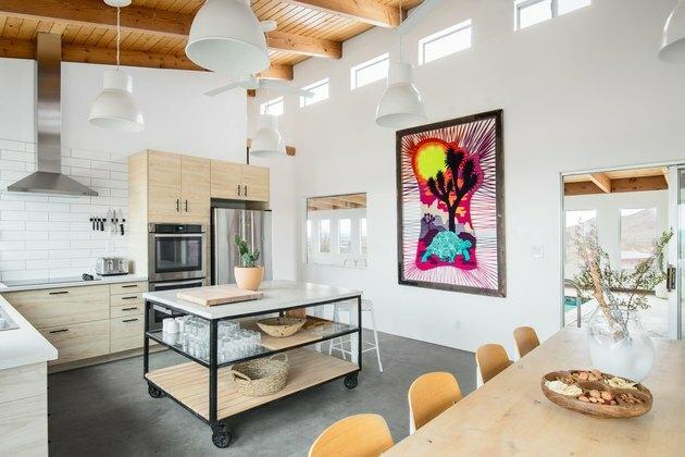 Cozinha minimalista com móveis de madeira, tetos com vigas de madeira, fogão e arte colorida