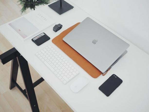 mesa com computador, teclado, telefone e outras ferramentas de mesa