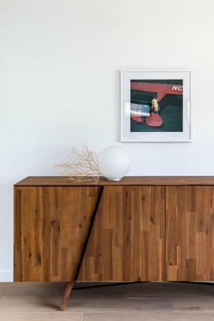 ideia de lâmpada de corredor com gabinete de painéis de madeira com luz globo contra a parede branca com pequena pintura suspensa no piso de madeira