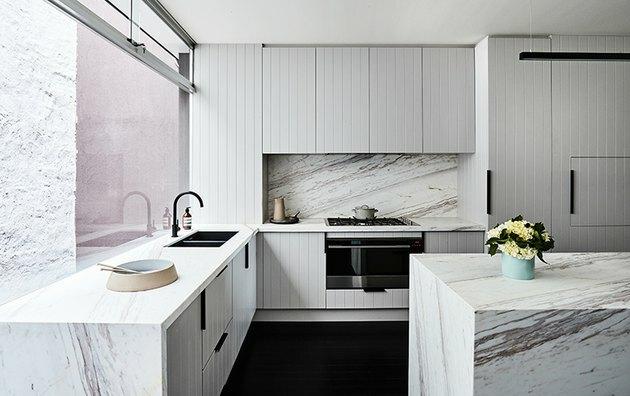 gabinete de beadboard cinza na cozinha com backsplash de mármore e ilha