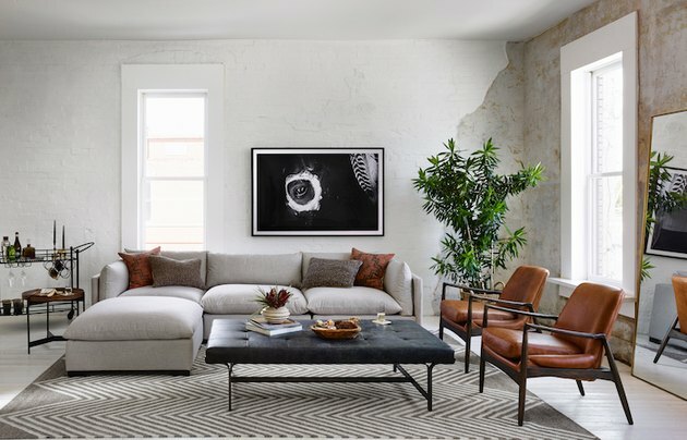sala de estar de estilo industrial com sofá branco e duas cadeiras