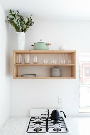Минималистична кухня с бели стени и рафтове за дърво със съдове и растения