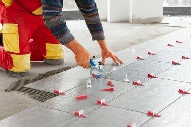 Carreaux de céramique. Carreleur plaçant le carrelage mural en céramique sur l'adhésif avec système de nivellement des carreaux de cils