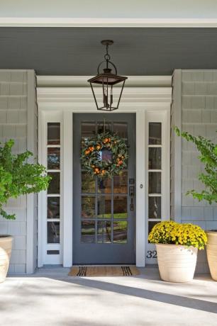 فكرة المنزل الخارجي التقليدية من الشرفة الأمامية مع النباتات وإكليل زخرفي على الباب