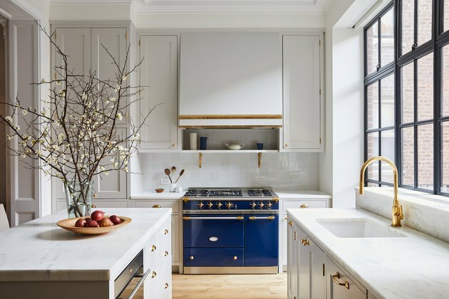 نوافذ سوداء في المطبخ الأبيض مع موقد أزرق وغطاء أبيض