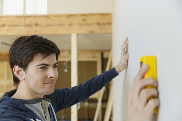 Jonge mens die met nagelvinder muur thuis onderzoeken