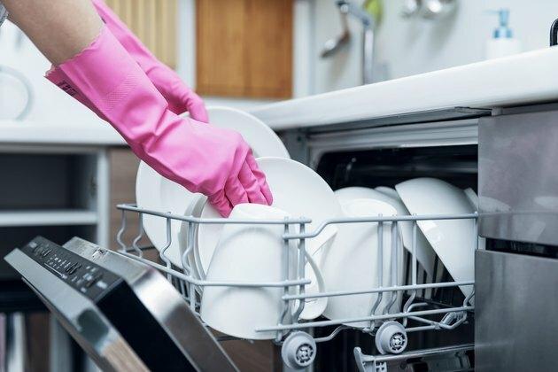 husmor, der tager rent opvask fra opvaskemaskine i hjemmekøkkenet
