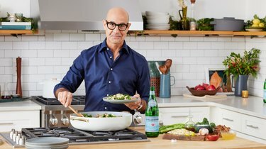 Näyttelijä Stanley Tucci pukeutuu laivastonsiniseen nappipaitaan ja seisoo keittolevyn edessä pastalautanen kädessään. Hänen edessään oleva valkoinen kattila on täytetty pastalla, ja hänen toisessa kädessään on kattilassa lepäävää puulusikkaa. Hänen vieressään tiskillä on pullo San Pellegrinoa sekä puinen leikkuulauta täytettynä kattilassa olevan pastan ainesosilla, mukaan lukien parsakaali, oliiviöljy, suola, valkosipuli ja pasta.