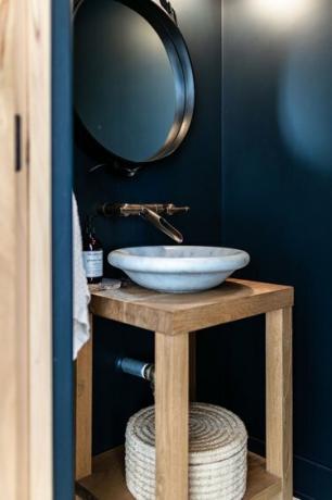 Un bagno dalle pareti blu con lavabo bianco e vanità in legno