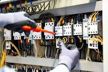 Eletricistas trabalham para conectar fios elétricos no sistema, quadro de distribuição, sistema elétrico no gabinete de controle.