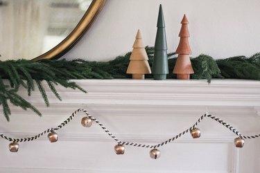Guirnalda festiva hecha de hilos de macramé de algodón verde y blanco trenzado con campanas, repisa con decoración festiva