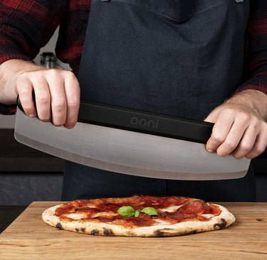 el hombre corta la pizza con una cuchilla basculante