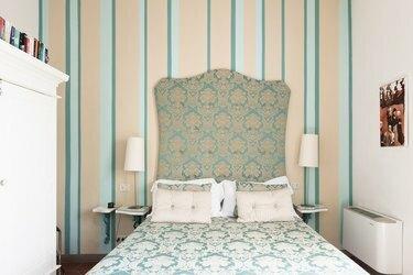 Grønt og cremet soveværelse med polstret sengegavl og stribet tapet