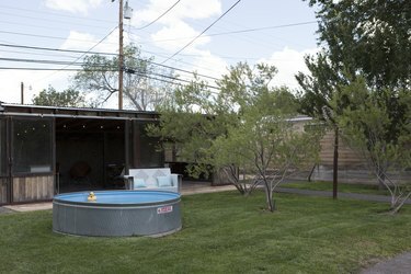 O curte cu o piscină cu rezervor de stoc și copaci mici