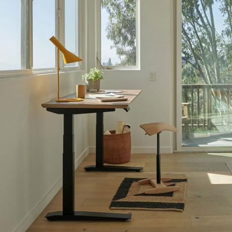 mesa de pé com abajur e banquinho perto da janela