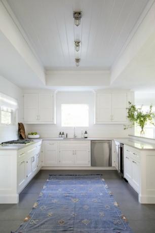 مطبخ أبيض مع تركيبات إضاءة صناعية محبوسة