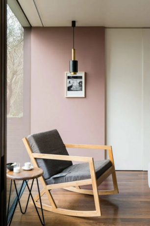 Quarto em estilo Bauhaus com parede rosa, lustre moderno e cadeira Bauhaus