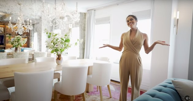 Misty copeland debout dans sa salle à manger avec une table en bois, des chaises blanches et un lustre en cristal