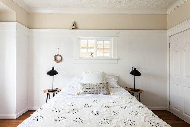 Quarto Boho com candeeiros de mesa pretos, paredes brancas e piso de madeira