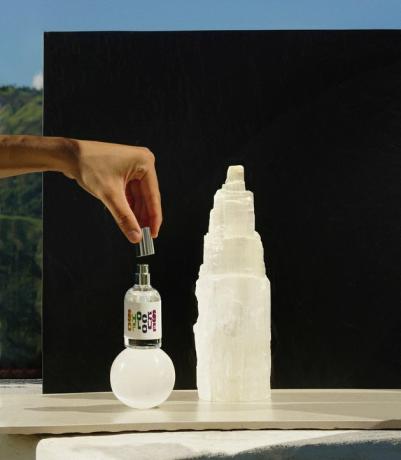 pessoa segurando um frasco de aromaterapia perto de cristais