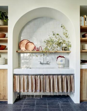Кухня в европейском стиле с голубыми плиточными полами и занавесками с кисточками под раковиной.