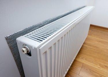 Oppvarmingsradiator i hvitt metall som inngår i et sentralvarmesystem med energieffektiv varmeisolasjon på veggen