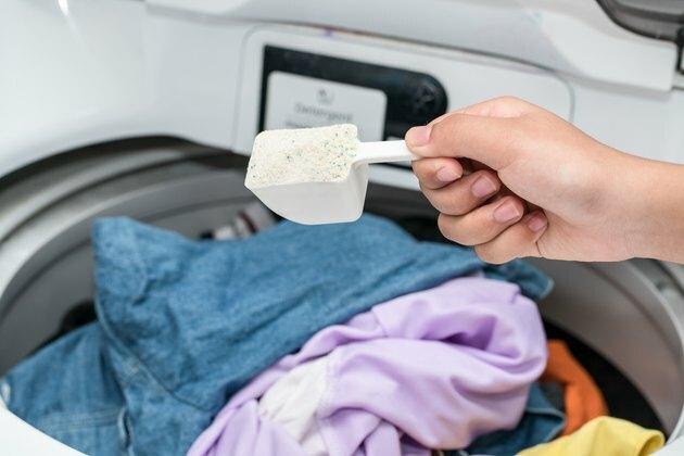 Deterjan çamaşır makinesi üzerinde tutan el Resim kırpılmış