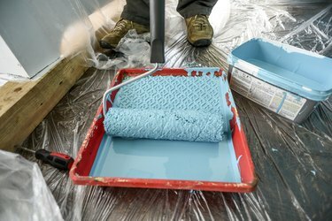 Priprava na barvanje sten v hiši z modro barvo z valjčkom.