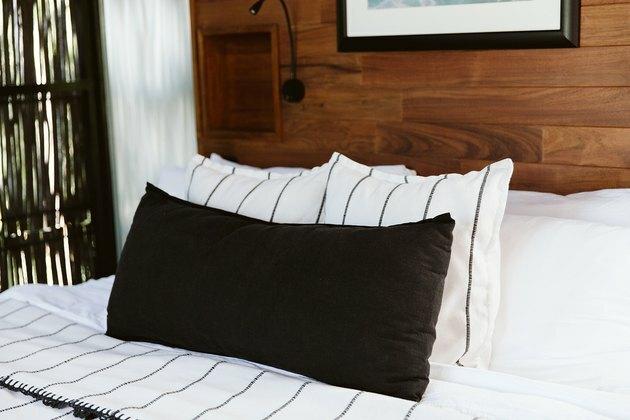 Cama branca e preta em quarto com painéis de madeira